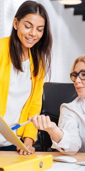 Two women discussing information on papers